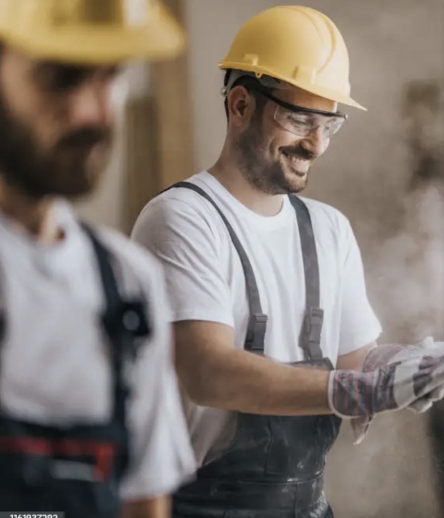 Ouvrier de construction avec un casque jaune et des lunettes de sécurité, travaillant sur un chantier