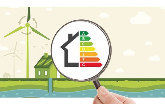 Loupe montrant une étiquette énergétique sur fond de maison et d'éoliennes