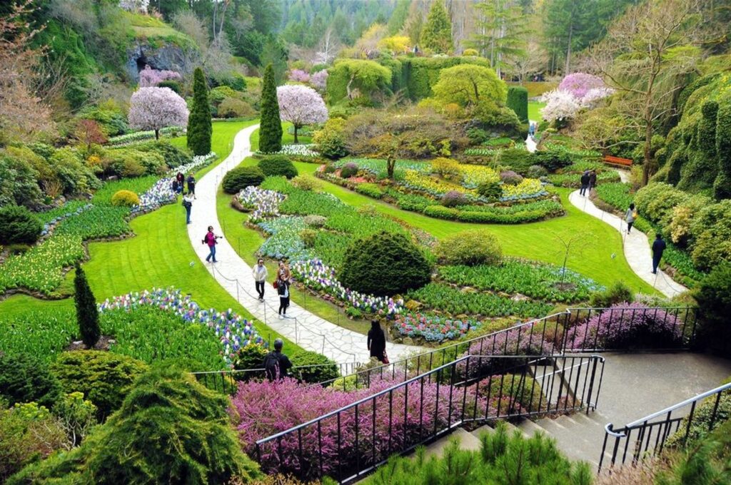 Un jardin magnifiquement aménagé avec des allées sinueuses, des massifs de fleurs colorées et des arbres en fleurs, avec des visiteurs se promenant le long des chemins