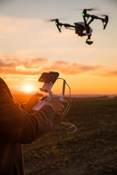 Personne pilotant un drone avec une télécommande au coucher du soleil