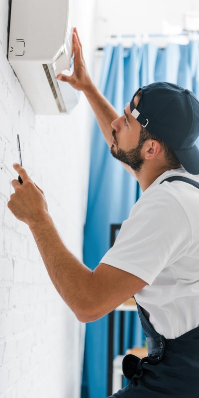 Technicien inspectant un climatiseur mural avec une lampe de poche