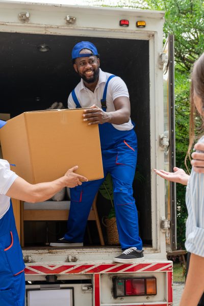 Man movers worker in blue uniform unloading cardboard boxes from truck.Professional delivery and moving service.