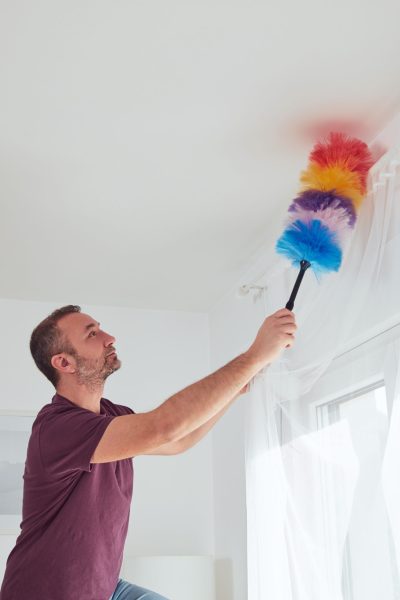 Man cleaning apartment with dusting broom.