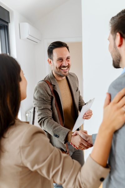 Agent immobilier serrant la main d'un couple dans une maison