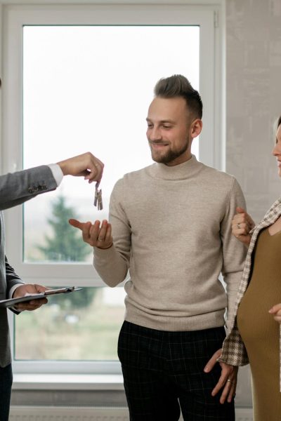 Agent immobilier remettant les clés à un couple dans une pièce lumineuse